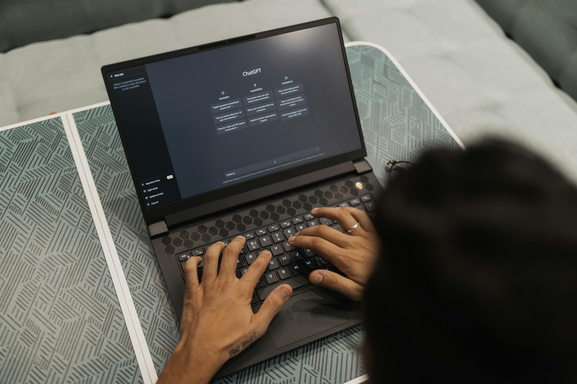 Pessoa digitando em laptop com tela do ChatGPT aberta em ambiente de trabalho moderno