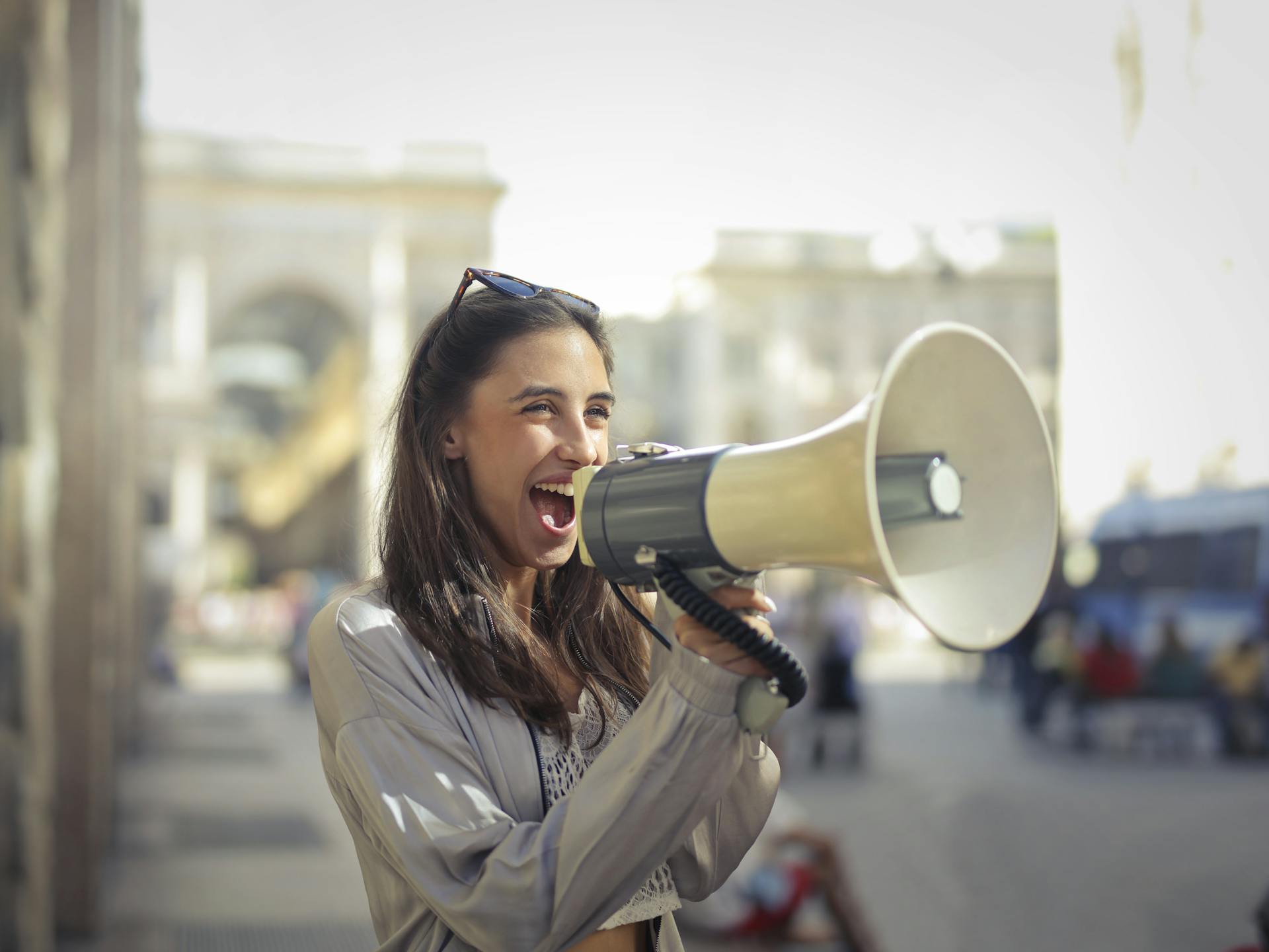 Mulher jovem sorridente usando megafone para divulgar mensagem em ação de marketing de conteúdo
