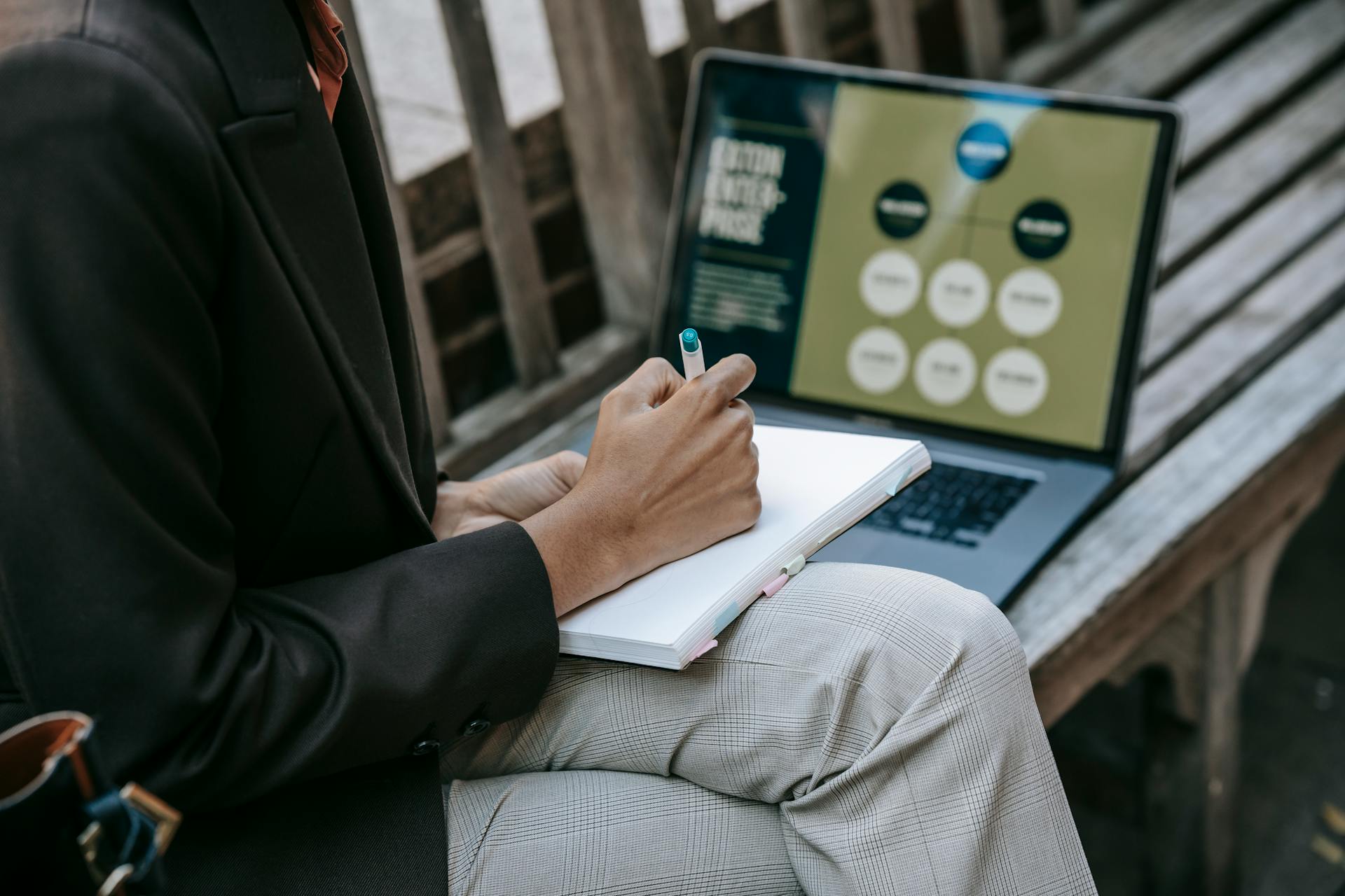 Pessoa planejando estratégia de conteúdo com anotações e laptop ao ar livre