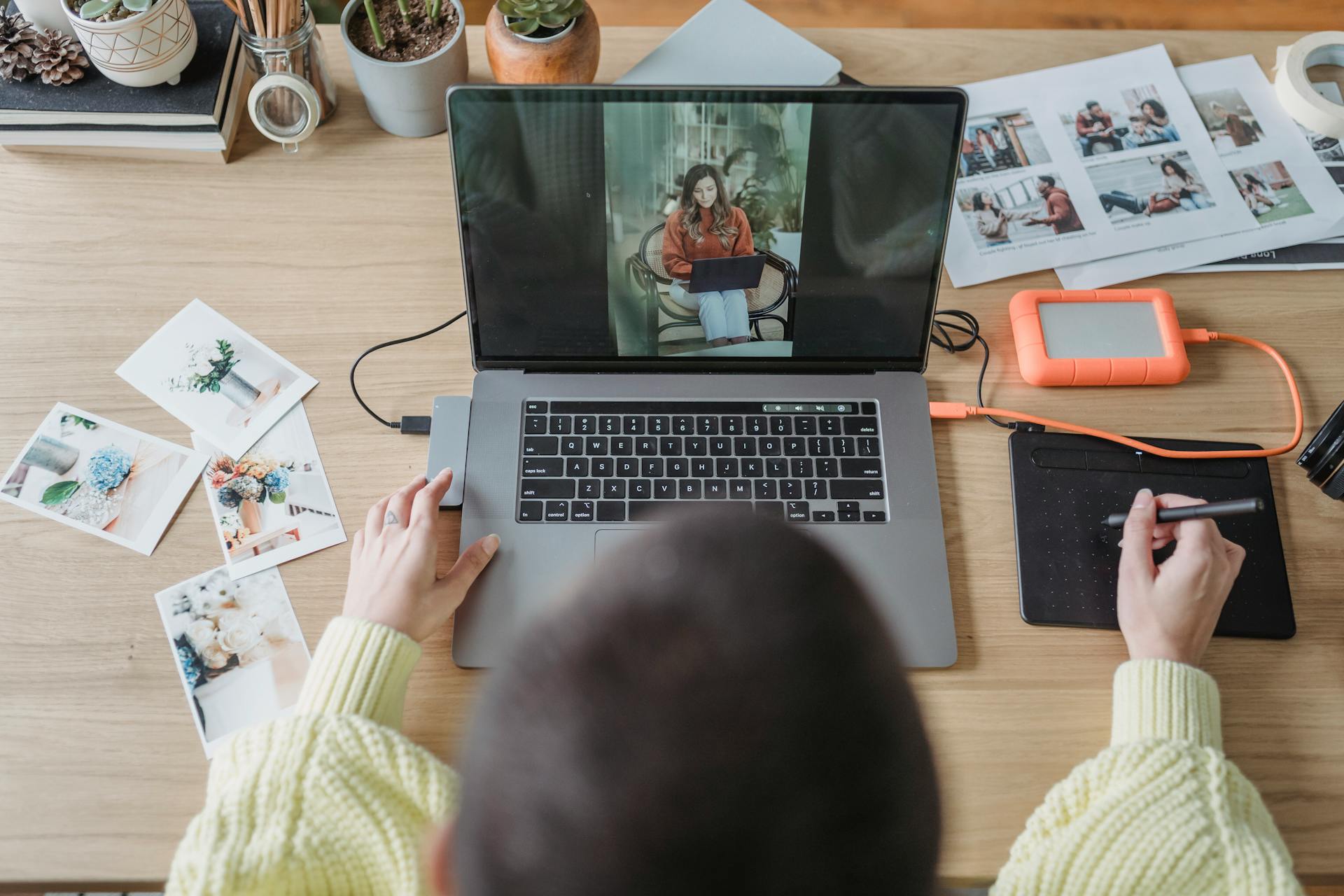 otógrafo editando imagens no notebook com fotos impressas e mesa digitalizadora ao lado