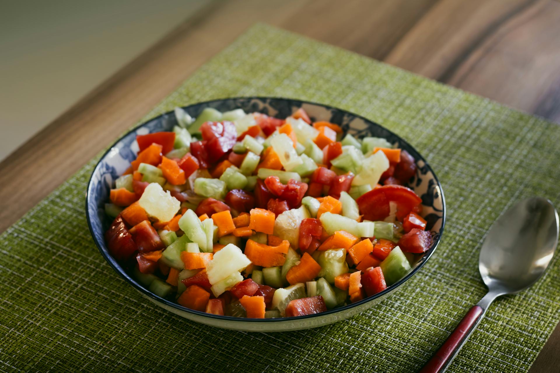 Salada colorida de legumes e frutas picadas em tigela sobre toalha verde na mesa