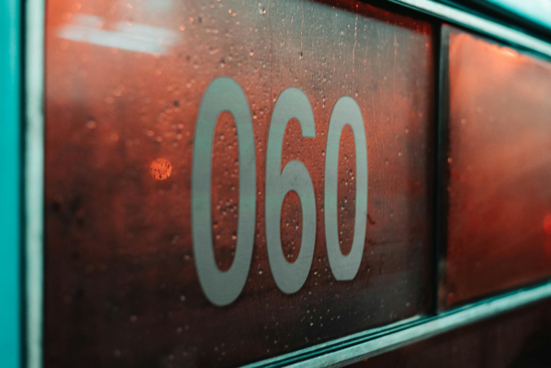 Número 060 em painel com efeito de condensação e luzes alaranjadas atrás.