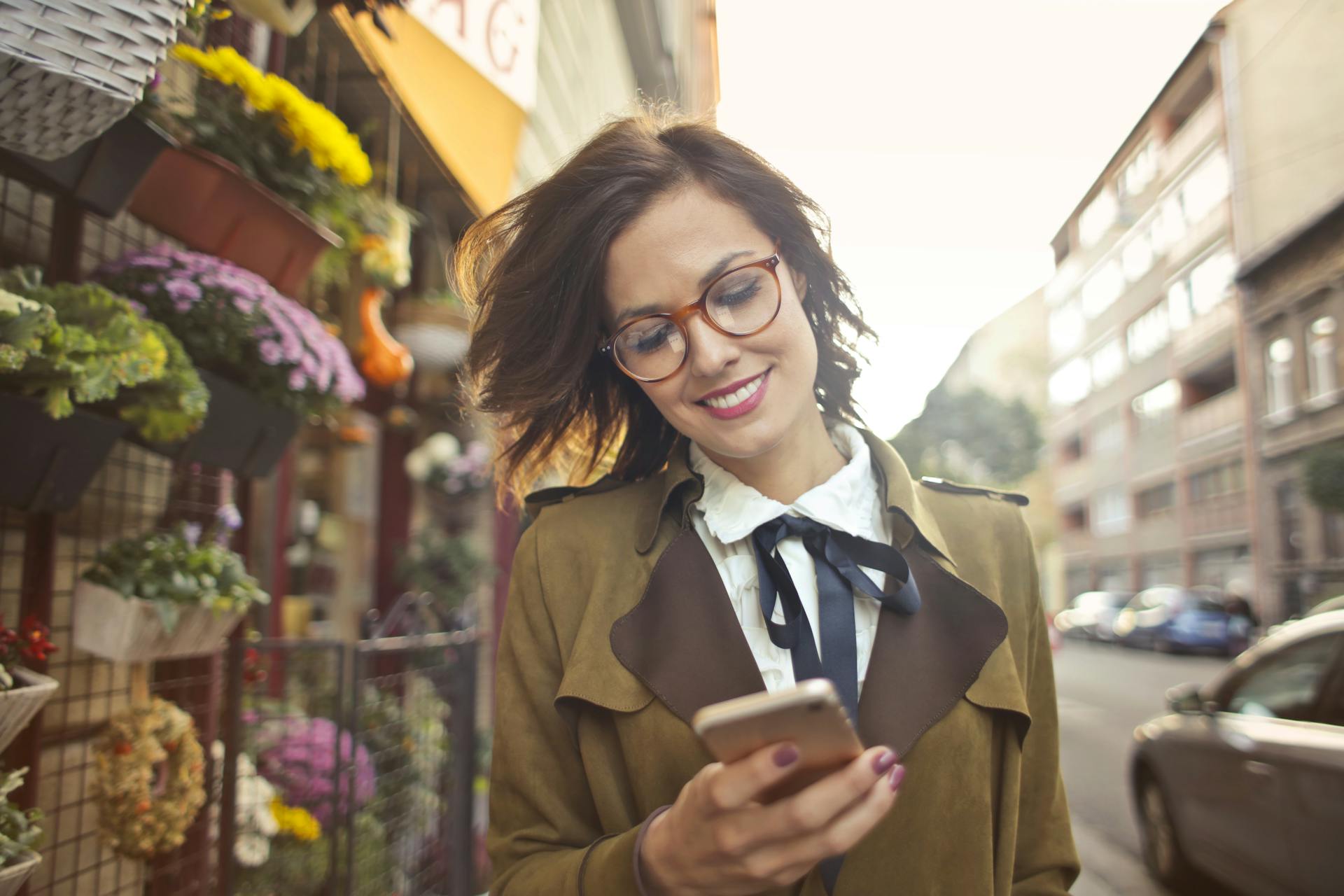 Mulher sorrindo enquanto usa o celular em frente a uma loja, representando vendas online com ChatGPT.