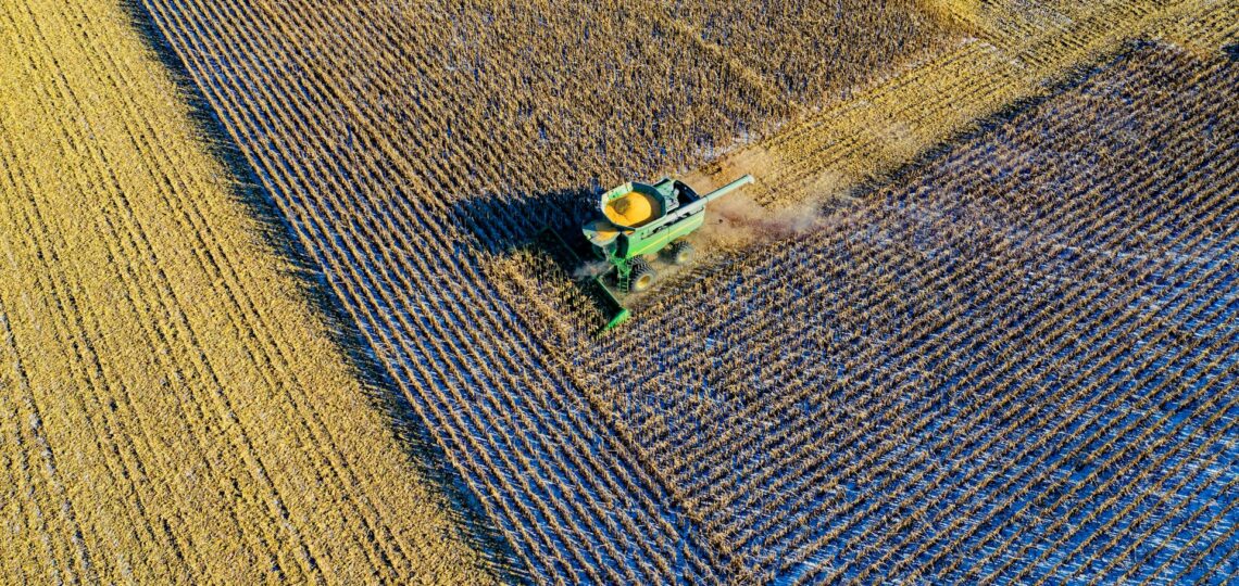 Colheitadeira em ação vista de cima em lavoura com padrão de plantio, representando agricultura de precisão com uso de tecnologia.