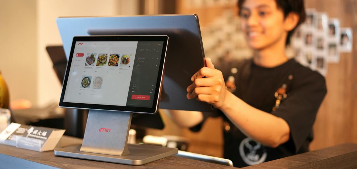 Atendente configurando cardápio digital em restaurante moderno com tela touch.