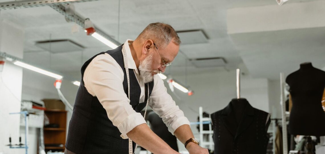 Alfaiate experiente desenvolvendo roupas sob medida em ateliê moderno com tecnologia.