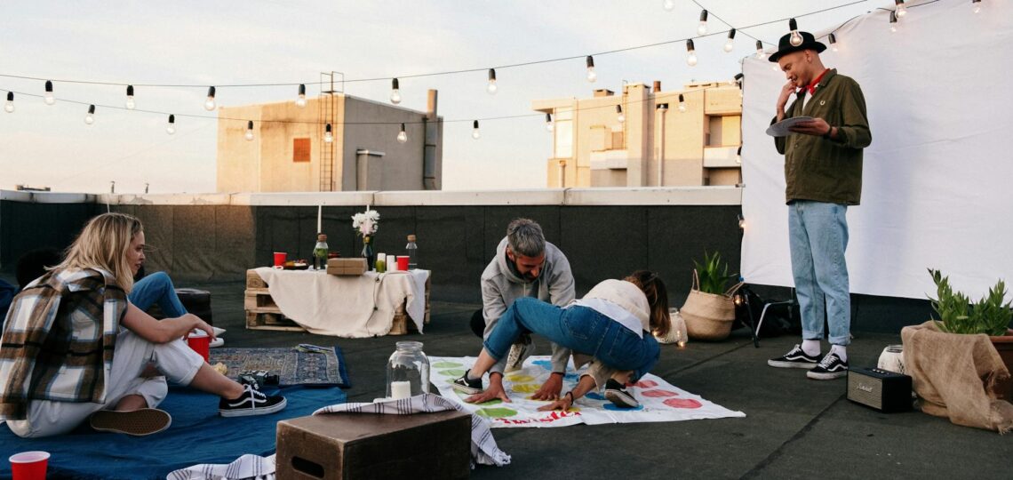 Amigos se divertindo em festa criativa no terraço com luzes e jogos