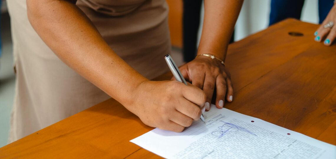 Pessoa assinando documento jurídico em mesa de advocacia moderna