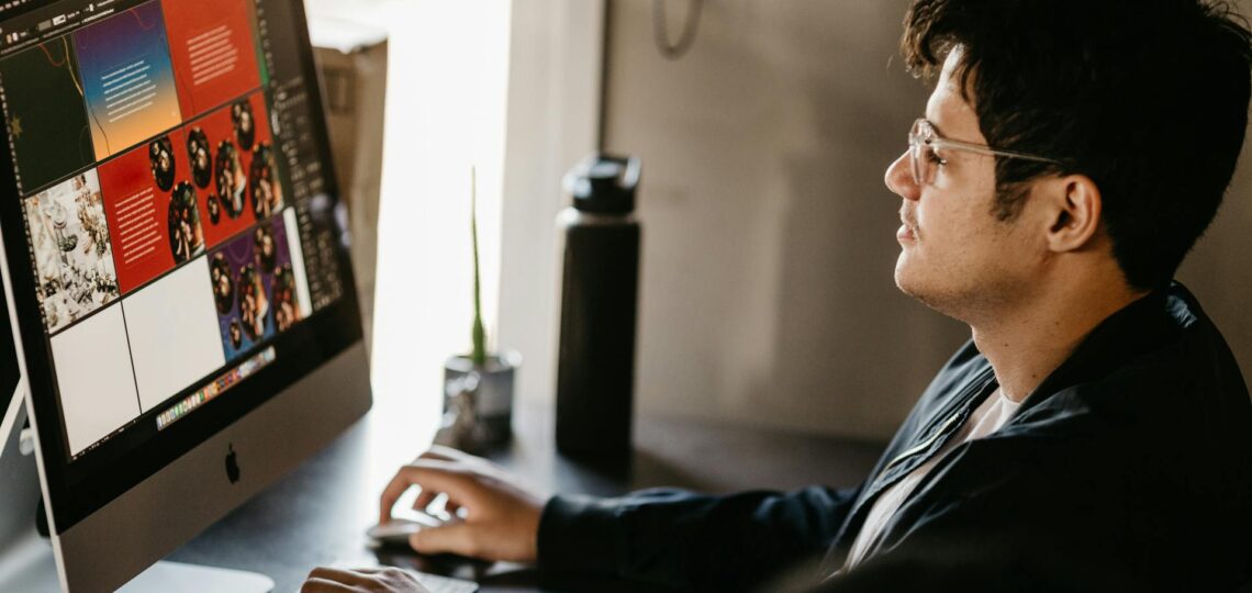 Designer gráfico cria composições visuais em computador com apoio de inteligência artificial para projetos criativos.