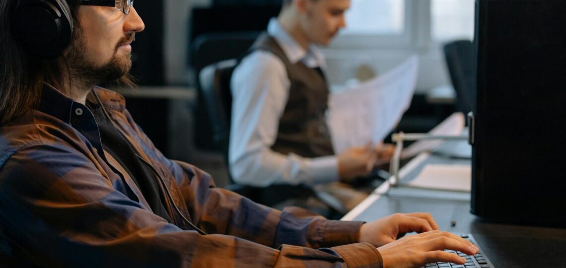 Profissional de TI usando computador em ambiente corporativo moderno.