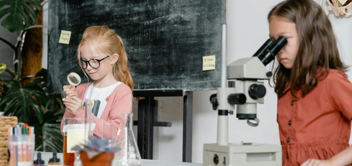 Duas alunas explorando ciência com lupa e microscópio em aula criativa