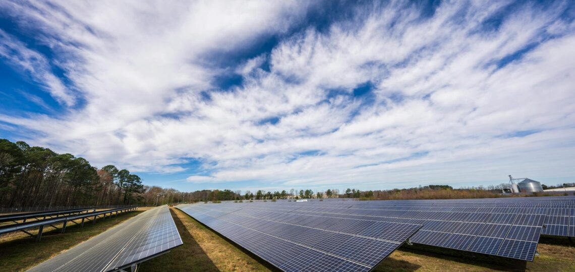 Painéis solares em campo aberto sob céu azul, simbolizando inovação em energia limpa e tecnologia ambiental.
