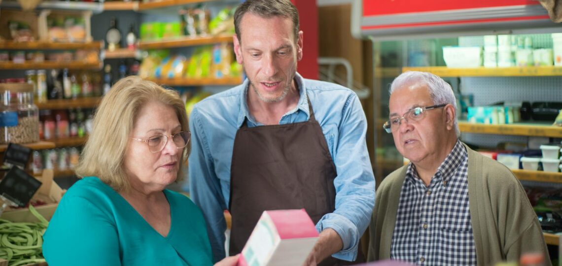 Vendedor explicando produto a clientes interessados em loja física