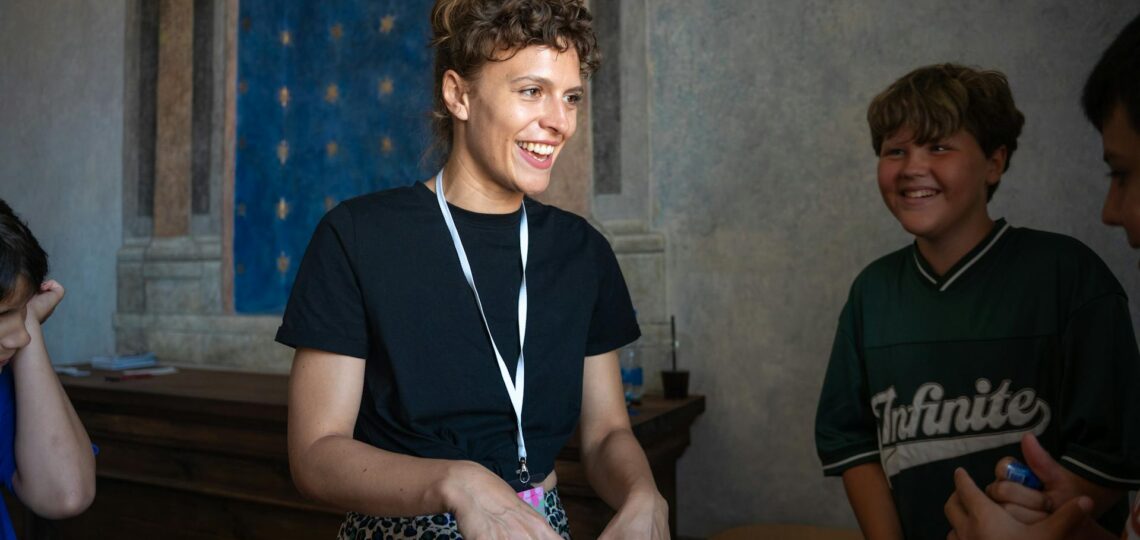 Pessoa sorridente interagindo com grupo em ambiente educativo, representando comunicação humana e conexão genuína com tecnologia