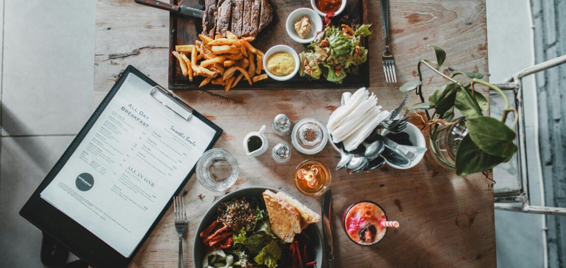 mesa de restaurante com pratos variados e cardápio ao lado, ilustrando conceito de menu inteligente com IA