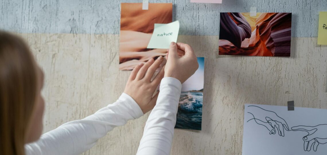 Artista visual organizando referências criativas em mural de inspiração.