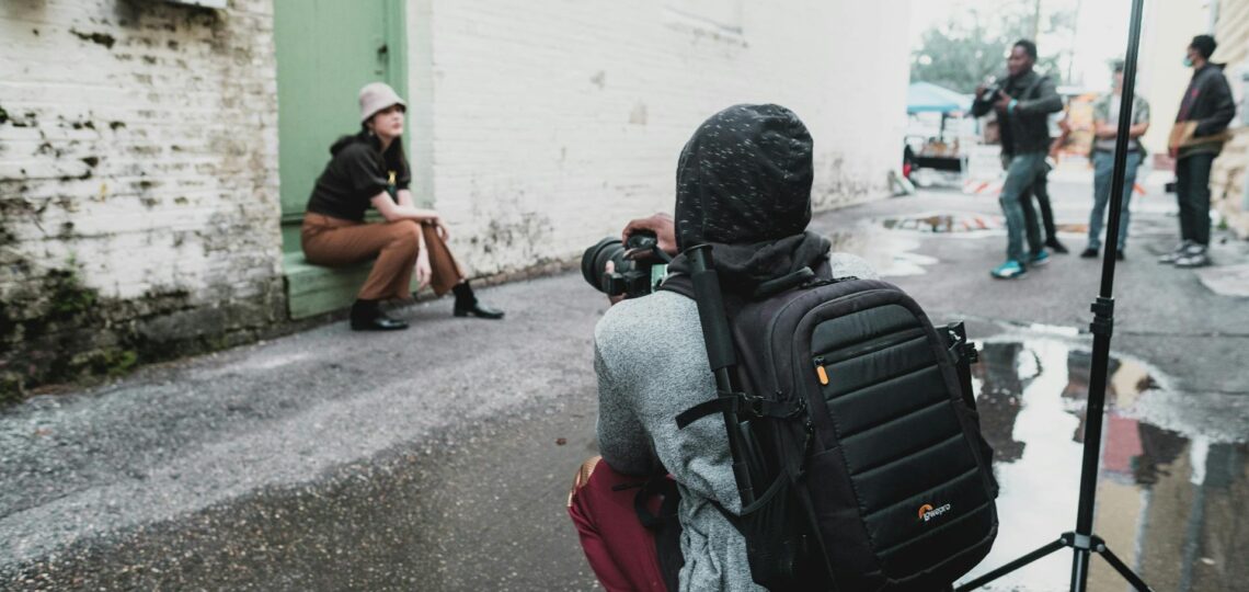 Fotógrafo dirigindo ensaio urbano com modelo em cenário de rua molhada
