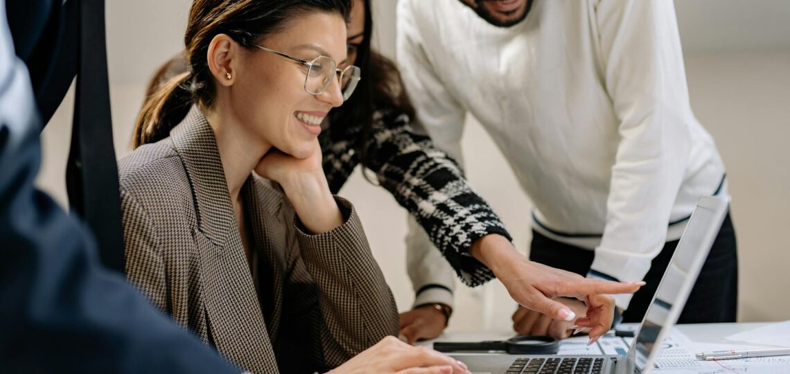 Profissionais sorrindo e colaborando no uso de inteligência artificial no trabalho.