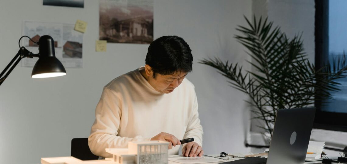 Arquiteto trabalhando em projeto arquitetônico moderno com computador e maquete.