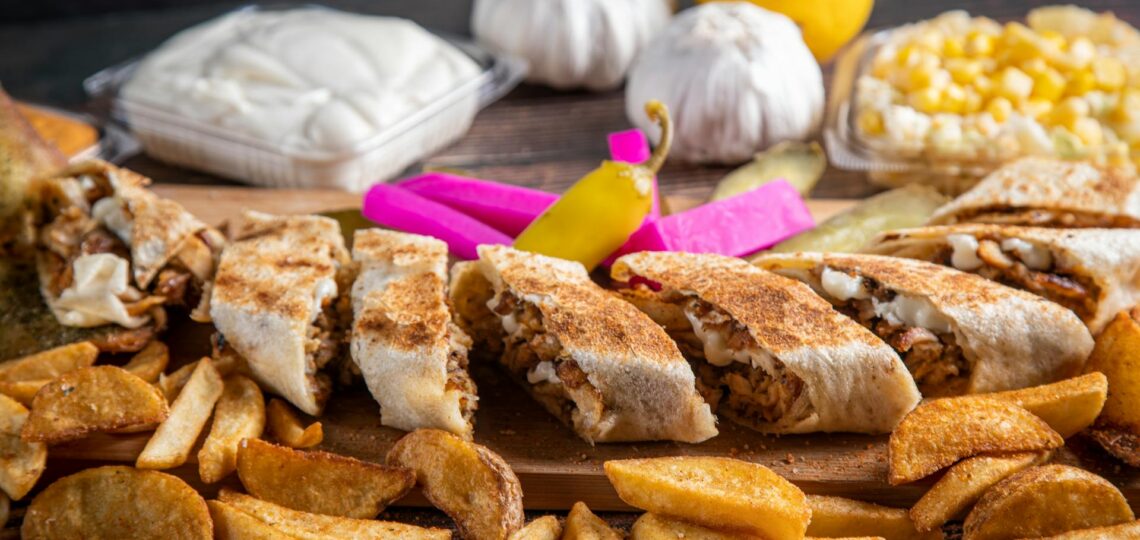 Sanduíches gourmet com batatas rústicas, pastas e picles em apresentação sofisticada