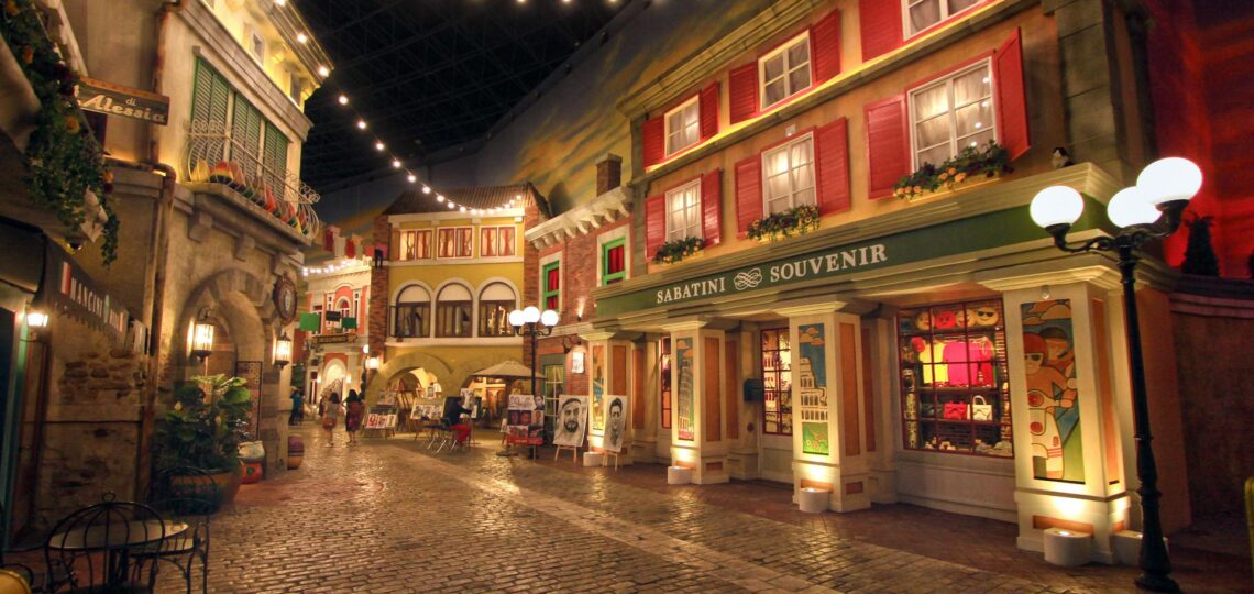 Rua turística iluminada com arquitetura temática europeia, representando uma experiência de viagem personalizada e imersiva.