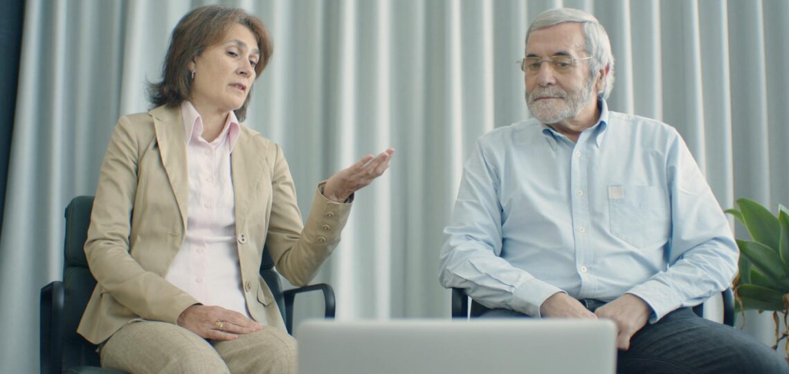 homem e mulher conversando olhando para um lapttop em um consultório