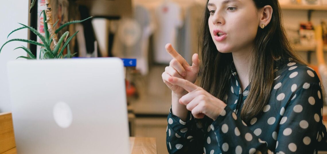 mulher sentada na frente de uma mensa conversando online com alguém