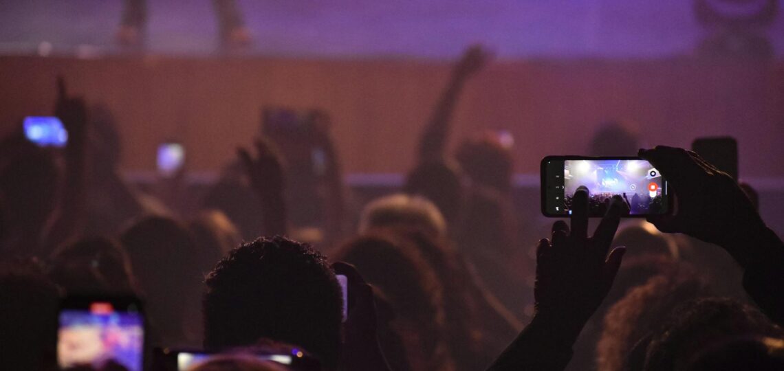 público no espetáculo com celular na mão registrano vídeo para engajar nas redes sociais