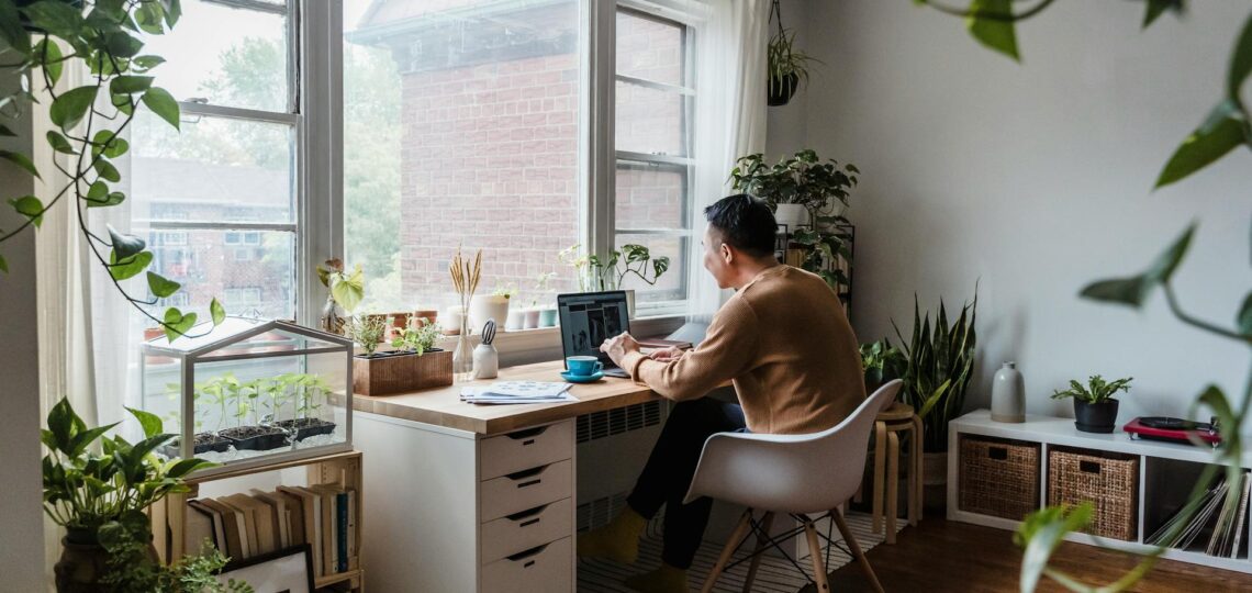 home office cercado de plantas de frente para uma janela aberta
