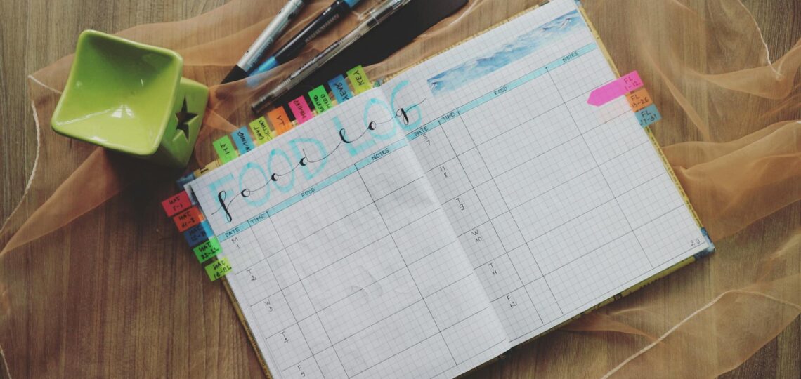 agenda preenchida com vários compromissos sobre uma mesa com canetas