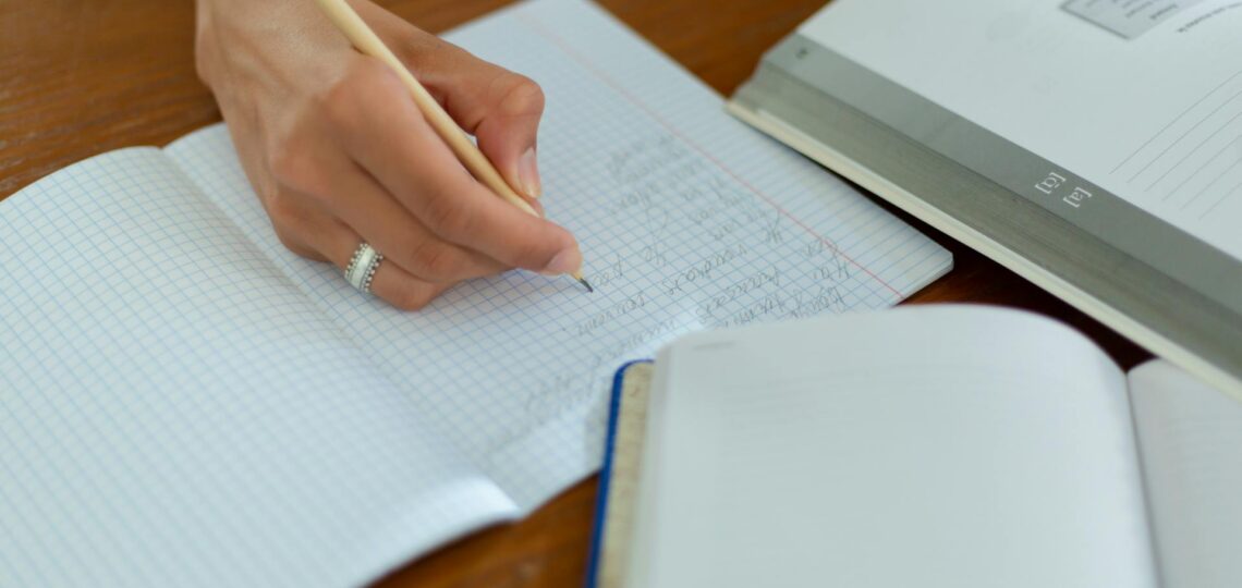 mão de mulher escrevendo em um caderno