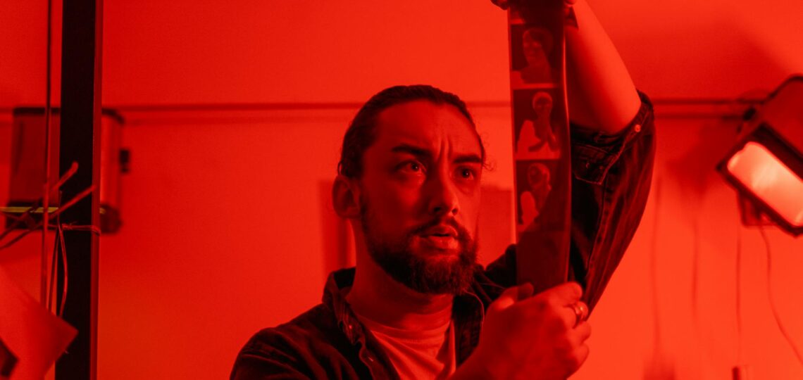 laboratório fotográfico com luz vermelha e fotografo revelando um filme