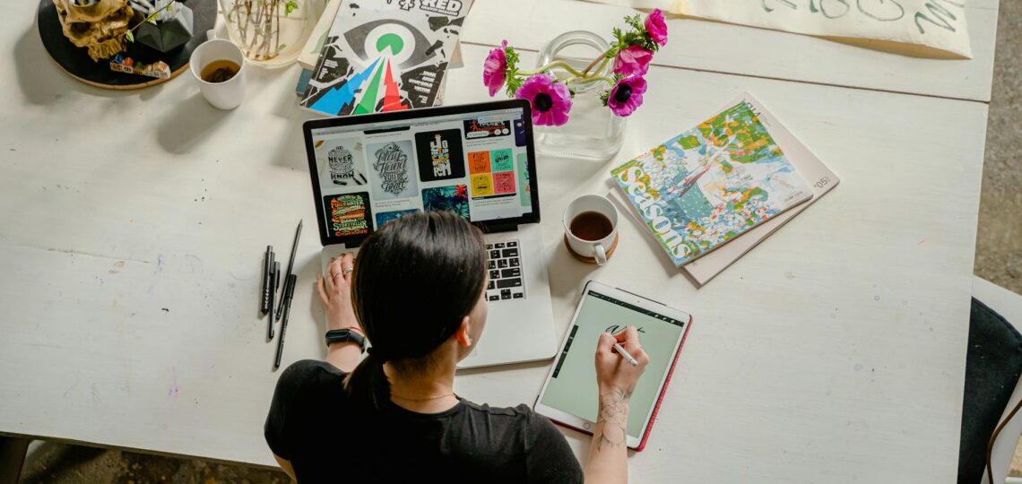 mulher designer grafica trabalhando em um tablet em frente a um laptop