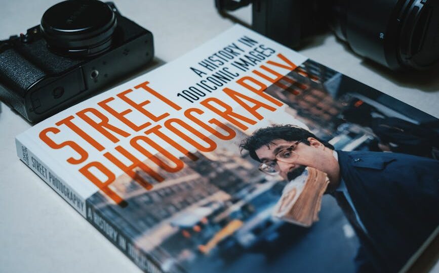 Book titled 'Street Photography' surrounded by cameras, highlighting iconic images.