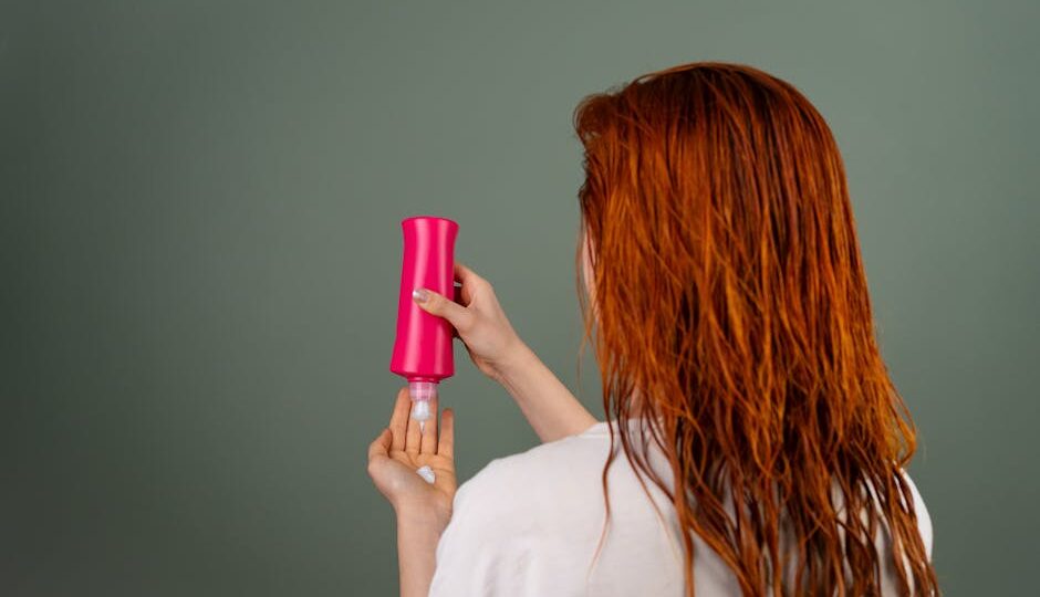 Adult woman with wet red hair applying conditioner. Hair care routine.