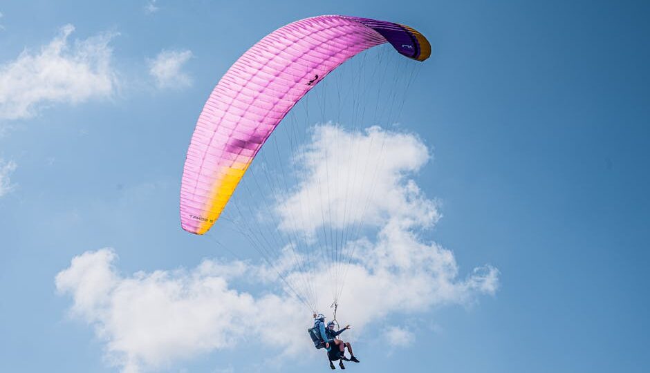 Experience the thrill of tandem paragliding with colorful parachute soaring high in the clear blue sky.