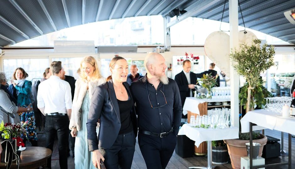 Chic indoor gathering featuring elegantly dressed guests mingling joyfully under a modern roof structure.