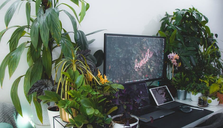 Modern desk setup with vibrant indoor plants and technology in a calming home workspace.