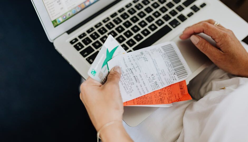 Close-up of hands holding receipts and a bank card in front of a laptop, representing online shopping and e-commerce.
