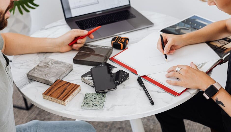 Two professionals collaborating on a design project with material samples and digital tools.