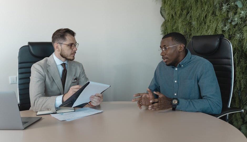 Two businessmen engaged in a discussion during a job interview in a contemporary office environment.