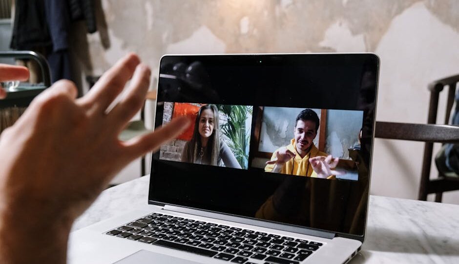 Hands gesturing during a video call on a laptop screen, showing two people in a virtual meeting.