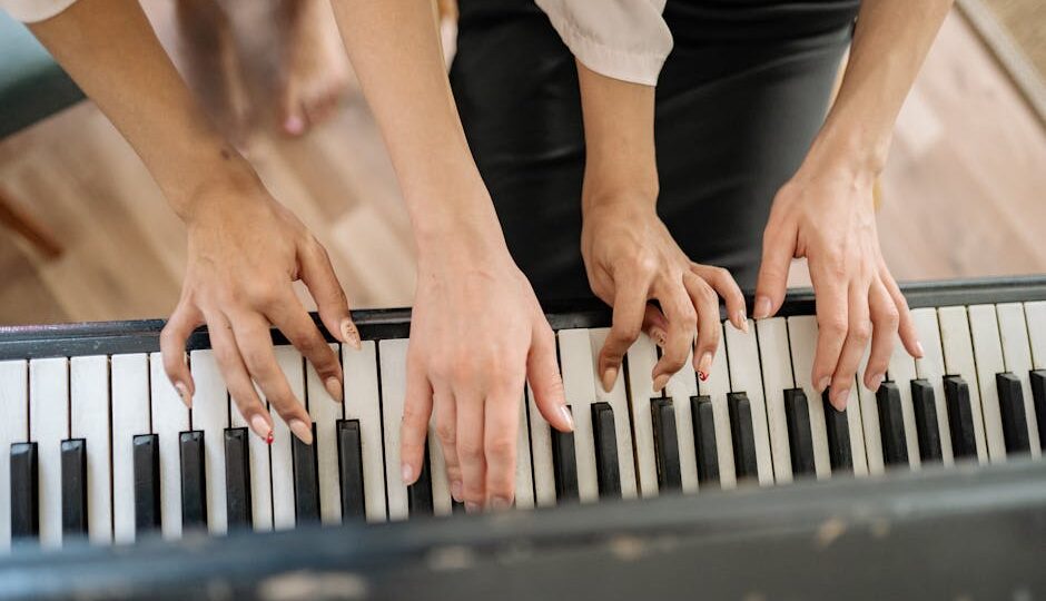 Close-up of multiple hands playing a piano, symbolizing teamwork.