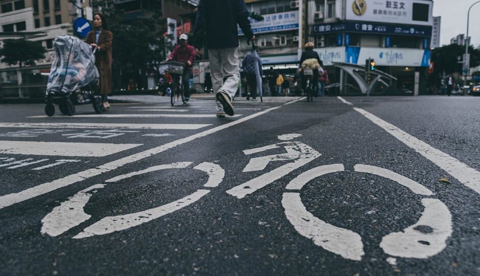Busy urban street scene in Taiwan with bicycle lane markings and pedestrians crossing.