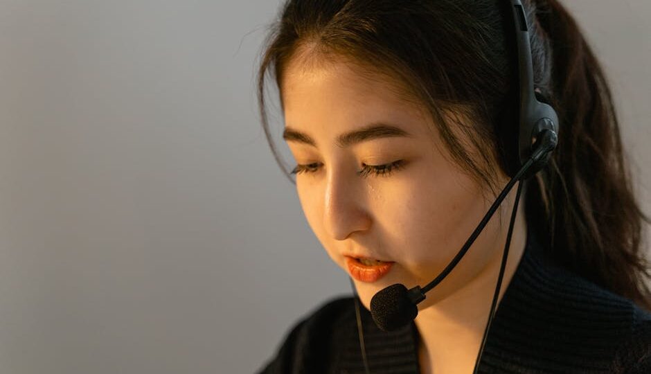 Focused young woman in headset working in customer support, speaking attentively.