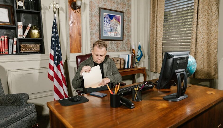 A lawyer in an office reviewing legal documents at a desk with an American flag nearby.