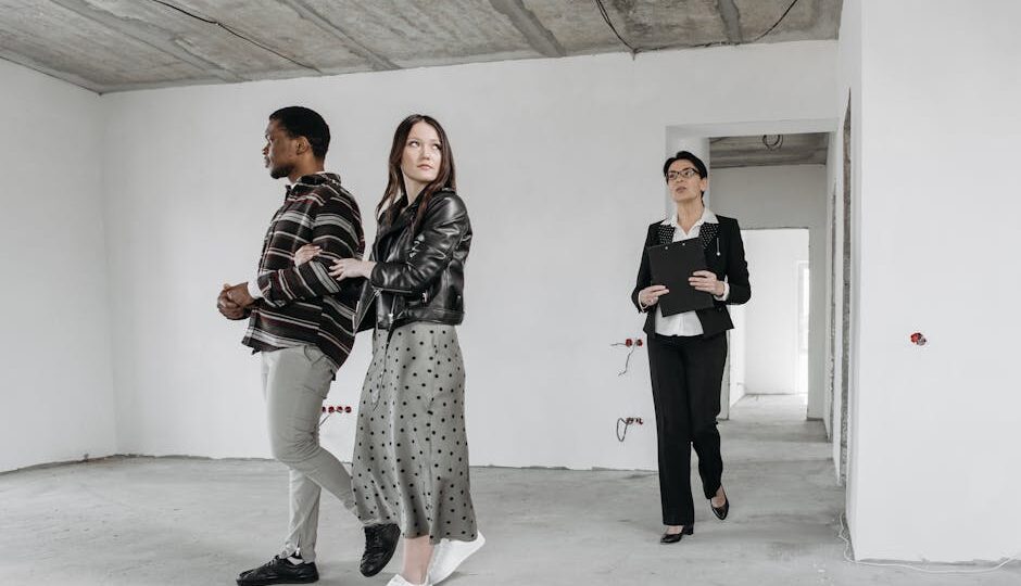 A real estate agent guides potential buyers through a modern home's unfinished interior.