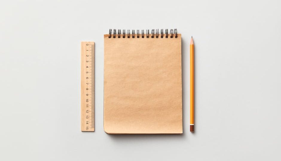 Flat lay of a spiral notebook, pencil, and ruler on a neutral background.