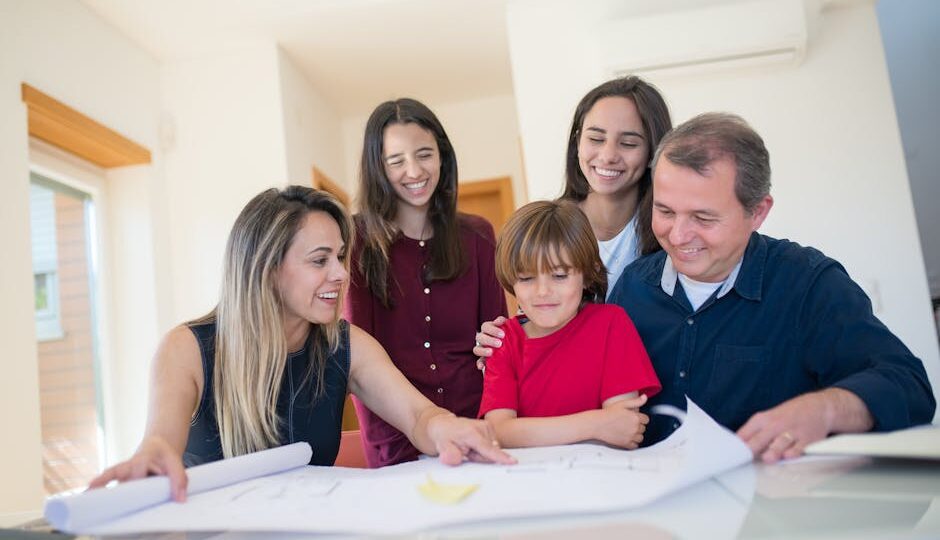 A joyful family gathered around a table reviewing a home blueprint together.