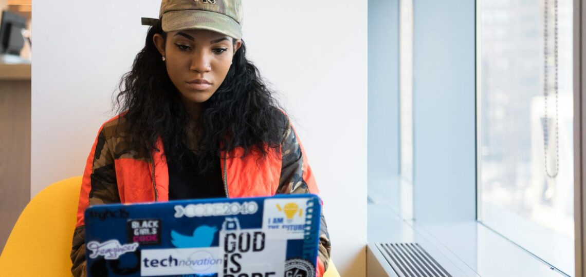mulher jovem sentada em uma poltrona mexendo em um laptop coordenando uma SaaS